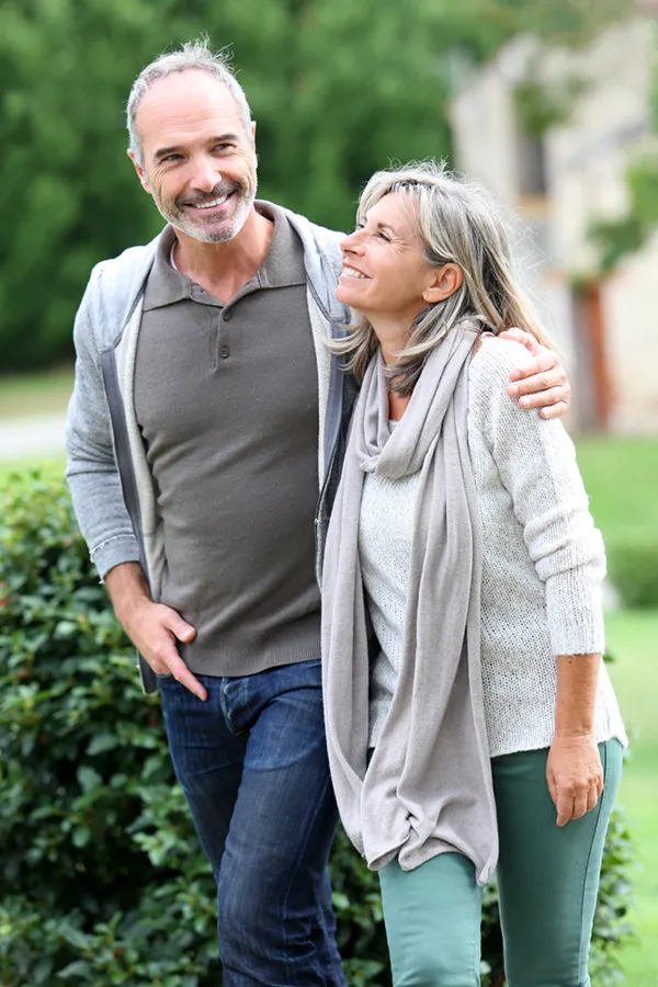 Bioidentical-Hormone-Therapy-Treatment A mature couple in gray toned clothes and jeans walk happily outside, happy with their successful bioidentical hormone treatments from AZENA Health & Longevity in Gainesville.