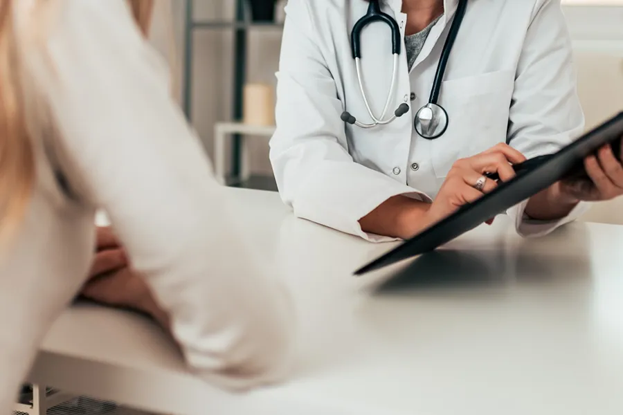 Concierge-Medicine-Doctor A doctor holds a tablet up to a patient, explaining a personalized care plan. Get concierge medicine services from AZENA Health & Longevity in Gainesville.