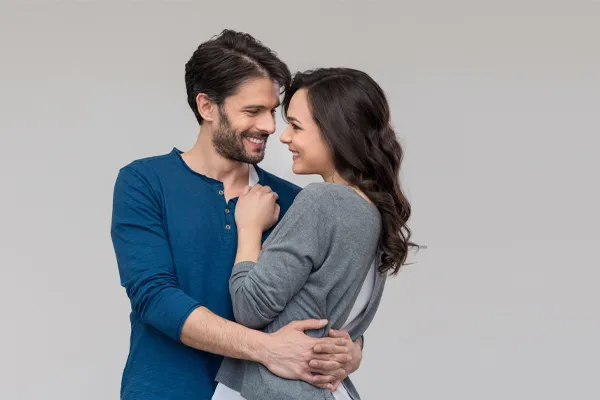 Erectile-Dysfunction-Doctor A man in a blue shirt embracing a woman in a gray shirt smiles due to his successful erectile dysfunction care from AZENA Health & Longevity in Gainesville.