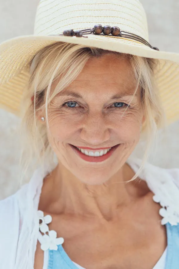 Menopause-Treatment A beautiful, smiling older woman with blonde hair and a sunhat, happy with menopause treatment from AZENA Health & Longevity in Gainesville.