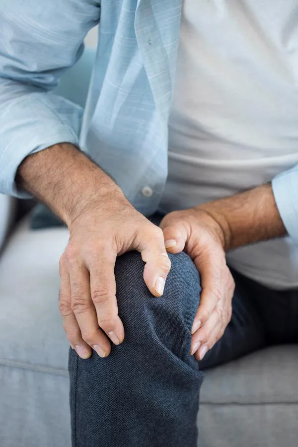 Osteoporosis-Pain A close-up of a man holding his knee while experiencing pain from osteoporosis. Get osteoporosis treatment from AZENA Health & Longevity in Gainesville.
