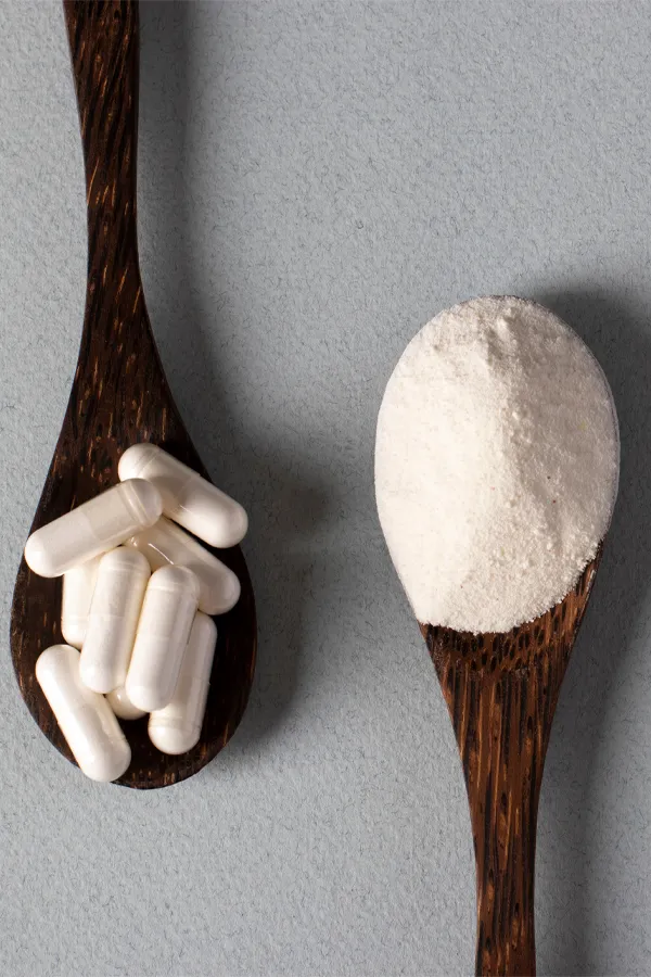 Peptide-Therapy-Treatment Two wooden spoons on a table, on with white powder and one with capsules, representing peptide therapy from AZENA Health & Longevity in Gainesville.